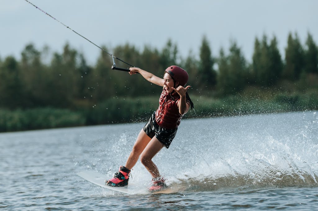 A wakeboarder skillfully rides the water, showcasing action and adventure on a sunlit lake.